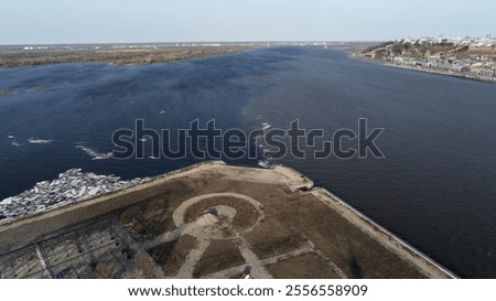 Large body of water with a small island in the middle. The water is dark blue and the sky is clear