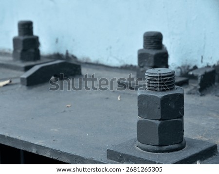 Large bolts and nuts, as structural fasteners. Made of metal and coated with black paint,