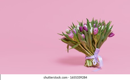 A large bouquet of colorful spring tulip flowers on a pink studio background. Gift for March 8 or birthday.