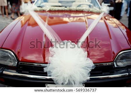 Large bow of veil put on old red Jaguar