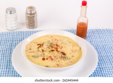 Large Bowl Of Chicken And Dumpling Soup On Country Style Blue Gingham Place Mat With Bottle Of Louisiana Hot Sauce.