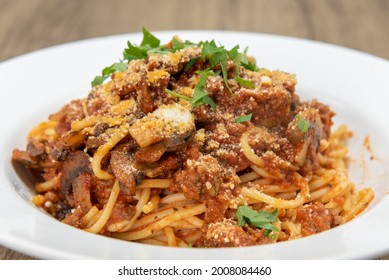 Large Bowl Of Fettuccini Bolognese Pasta Covered In Sauce, Mushroom, And Garnishment For A Hearty Meal.