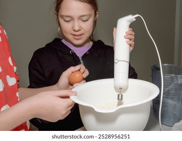 Large bowl with flour and breaking eggs, kitchen mixer. The girls make the dough. - Powered by Shutterstock