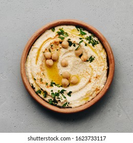 Large bowl of homemade hummus garnished with chickpeas, red sweet pepper, parsley and olive oil - Shutterstock ID 1623733117
