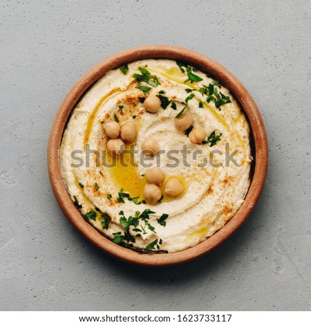 Large bowl of homemade hummus garnished with chickpeas, red sweet pepper, parsley and olive oil Stok fotoğraf © 