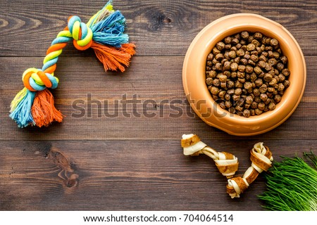 large bowl of pet - dog food with toys on wooden background top view mockup