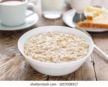 Large bowl of tasty and healthy oatmeal for Breakfast, morning meal. Side view, close up, wooden rustic table.