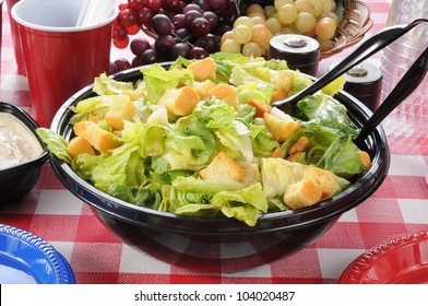 A large bowl of tossed green salad on a picnic table on a summer day