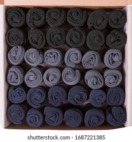 large box with many men's gray, black and blue socks rolled up, flat lay