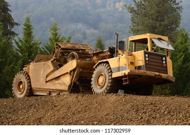Large Box Scraper Tractor Works At Moving Soil And Rock For A New Commercial Housing Development.