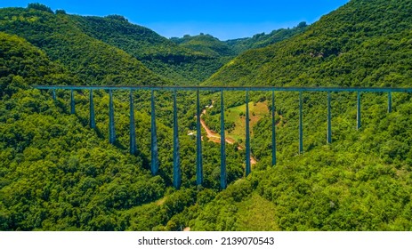 Large bridge with train tracks between mountains