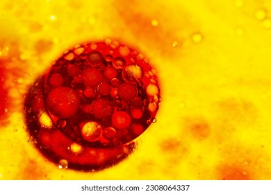 Large bright red bubble with small bubbles floating on the surface of the yellow liquid. Bacterium, molecule, oil.