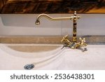 Large bronze faucet on a stone washbasin in the bathroom