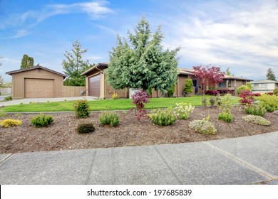 Large Brown House With Garage. View Of Front Yard With Lawn And Flower Bed