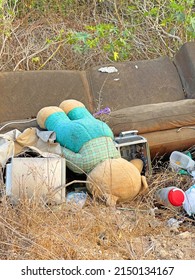 Large brown sofa, soft teddy bear are thrown out in trash heap in summer outdoors. Pollution of nature, environment, garbage. Poor ecology in Cyprus, Paphos city. Stuffed animals are thrown away.