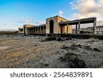 A large building with a courtyard in the middle of a desert. The building is old and abandoned