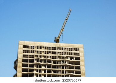 A large building is currently under construction, and there is a crane on top of it performing essential tasks to aid the building process