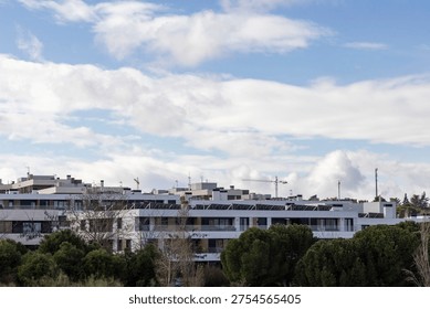 A large building with many windows and a cloudy sky in the background. The building is white and has a lot of windows
