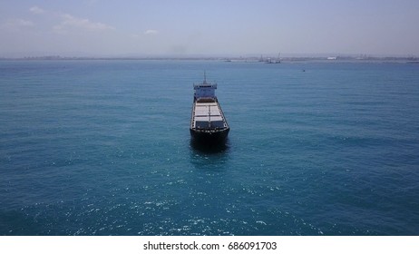 Large bulk carrier ship docking outside port in open ocean
