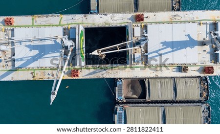 large bulk carrier ship transferring dark bulk cargo like coal or minerals into smaller barges alongside it in the open sea, representing maritime logistics and global supply chain.