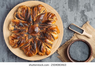 A large bun with poppy seeds on a plate on a dark background. Top view, horizontal. - Powered by Shutterstock