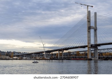 A large cable-stayed bridge being built over a calm river near New Westminster, Greater Vancouver, BC, Canada.