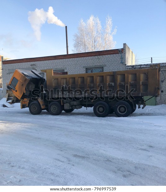 A large career dirty truck got up for winter\
repairs on the street. The cabin  dump truck is pushed forward to\
repair the engine.