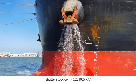 Large cargo ship discharging ballast water out from the Anchor's hub
