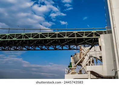 A large cargo ship passing under the bridge, photograph taken from the deck of the ship.