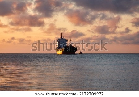 Large cargo ship sailing at sunset. Baltic sea. Panoramic view from a sailboat. Freight transportation, logistics, global communications, economy, business, industry
