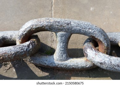 Large Chain links laying on stone, one large chain link with two chain links either side.