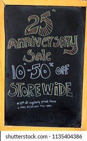 Large Chalkboard Sign Advertising 25th Anniversary Sale In Store Downtown.