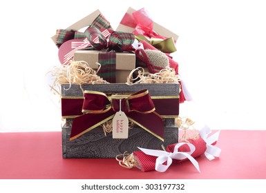 Large Christmas Gift Hamper With Traditional Red And Green Wrapping On Red Wood Table. 