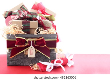 Large Christmas Gift Hamper With Traditional Red And Green Wrapping On Red Wood Table, With Copy Space. 