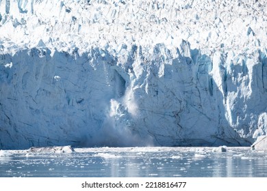 Large Chunks Of Ice Fall From The  Face Of A Glacier Black Cracks Cross The Surface Of The Cliff Front Edge Whilst The Upper Ridge Is Rough And Pot Marked. 