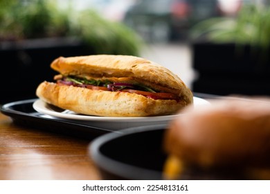 Large ciabatta sandwich with salad, fresh vegetables and onions, and meat.