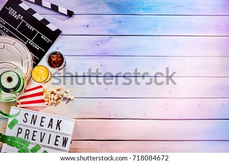 Large circular metal film reel next to multiple food and drink containers and sign that says sneak preview in black letters