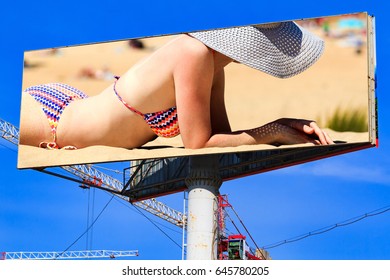 Large City Billboard With Woman In Bikini On A Beach And With Blue Sky Behind It.