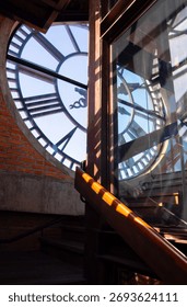 Large clock face is seen through window tower casting intricate shadows. scene captures blend of industrial and historical Clock tower
