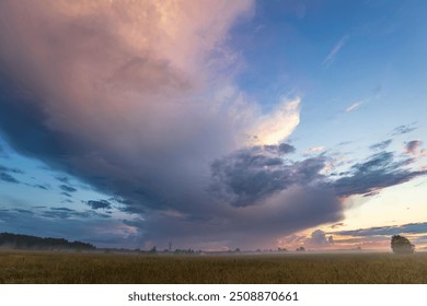 A large cloud is in the sky, and the sun is setting. The sky is a mix of blue and pink, creating a serene and peaceful atmosphere