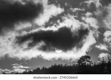 A large cloud with a sun in the middle. The sun is partially visible. The sky is cloudy