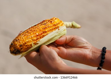 Large Cob Of Corn On The Grill. Closeup Of The Hand Of An Indian Woman Passes The Corn To A White Girl. Asian Street Food. Trolley On The Beach GOA.