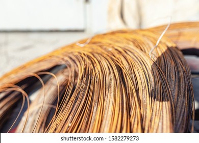 A large coil of old rusty wire lies on a wooden pallet