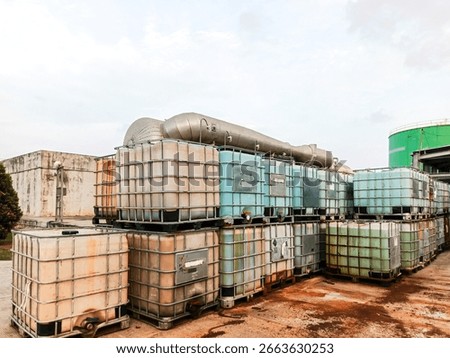 A large collection of intermediate bulk containers (IBCs) stacked outdoors in an industrial storage area, possibly for chemicals or waste liquid. 