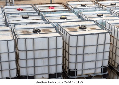 A large collection of white intermediate bulk containers (IBCs) with metal cages, neatly arranged for industrial storage or transport of liquids.