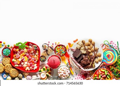 Large colorful selection of kids party food and sweets with cookies, ice cream, lollipops and candy isolated on white as a lower border with copy space - Powered by Shutterstock