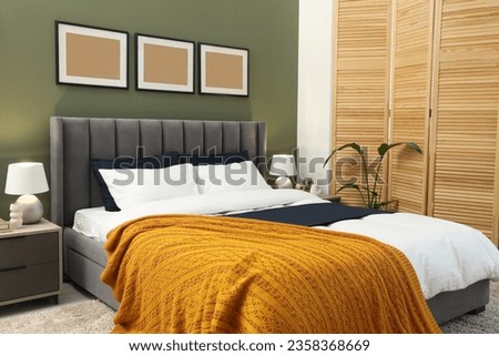 Large comfortable bed, houseplant and lamps in stylish room. Interior design
