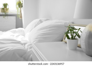 Large comfortable bed with soft pillows and blanket indoors