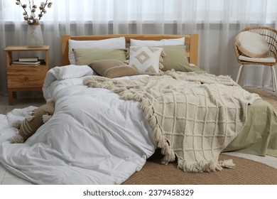 Large comfortable bed with soft pillows, duvet and blanket in room. Home textile
