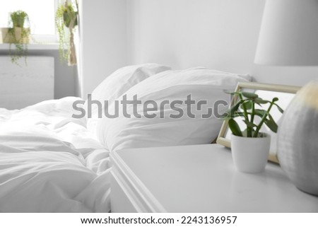 Large comfortable bed with soft pillows and blanket indoors